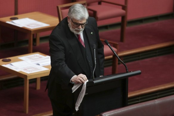 Senator Kim Carr wipes down the lectern before speaking during debate in the Senate in 2020.