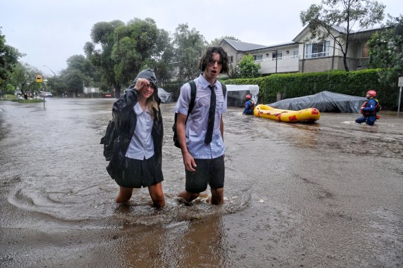 Student trudge through floodwater on Macpherson Street, Warriewood.