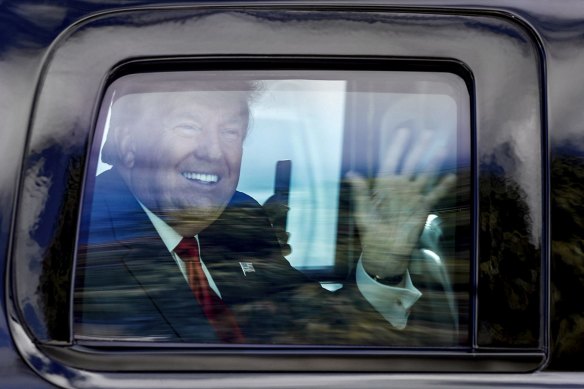 Former President Donald Trump waves to supporters as his motorcade drives through West Palm Beach after he left office.