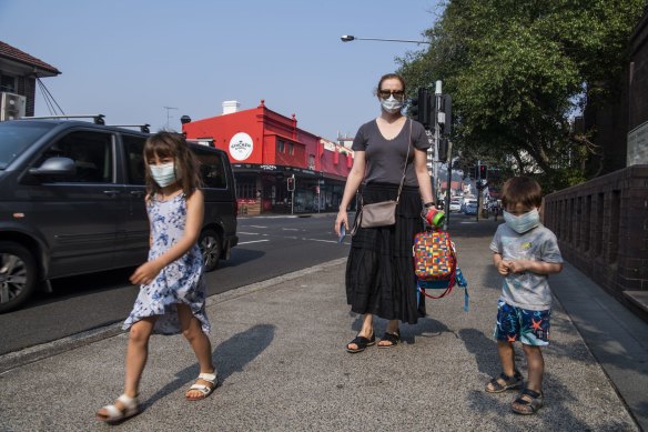 Emily with her children Abigail and Alexander wear face masks on their way to school in Bondi.