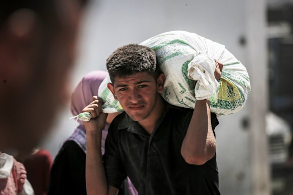 A Palestinian man carries food collected from a humanitarian aid distribution point.