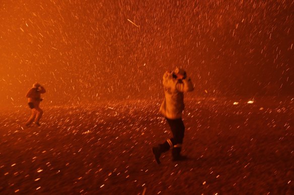 Firefighters overwhelmed by flames at bushfire in Orangeville in NSW in early December.