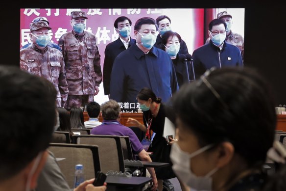 Journalists chat near a screen showing President Xi Jinping at the Huoshenshan Hospital in Wuhan before a press conference for the white paper on fighting Covid-19. 