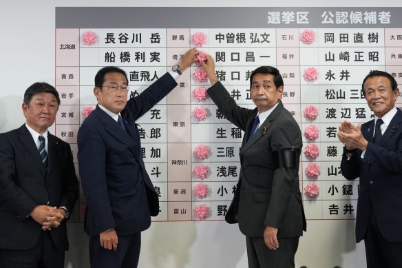 Fumio Kishida, second left, Japan’s prime minister, placing a red paper rose on an LDP candidate’s name, to indicate a victory in the upper house election, at the party’s headquarters in Tokyo.