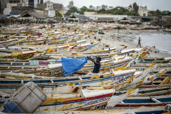 A fisherman dries a sheet next to fishing boats on the beach in Dakar, Senegal.