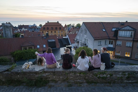 People sit along a street in the town of Visby in Gotland, Sweden. 