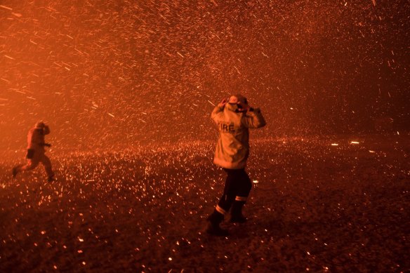 Firefighters from FBNSW run for safety as the Green Wattle Creek fire exploded from the bush in Orangeville filling the air with millions of embers.
