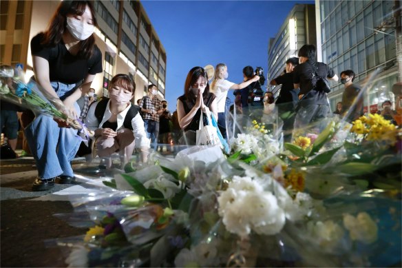 People pray at a makeshift memorial at the scene where former Prime Minister Shinzo Abe was shot while delivering a speech to support the Liberal Democratic Party’s candidate during the election on Friday.  