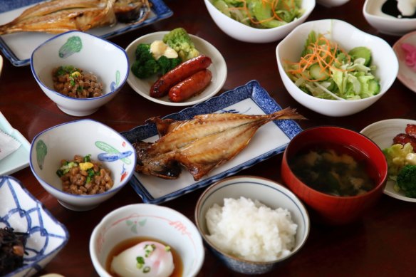 Japanese ryokan breakfast dishes including cooked white rice, grilled fish, boiled egg and miso soup.