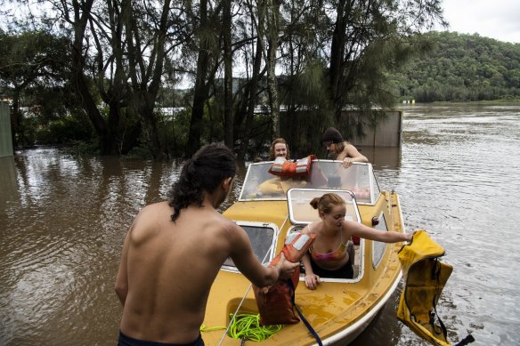 Wisemans Ferry residents Tabatha Shephard with Boyfriend Jye Whitton and their friend Ben collect supplies as their home on Saint Albans Road is closed due to flooding.