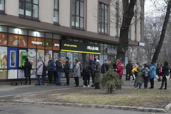 People line up to withdraw their money from an ATM in Kyiv.