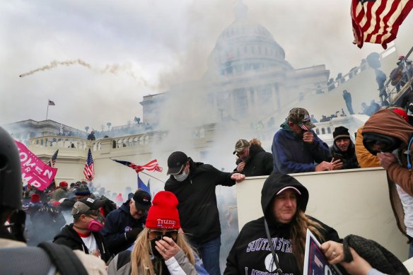 Trump supporters cover their faces to protect from tear gas during a clash with police officers in front of the US Capitol.