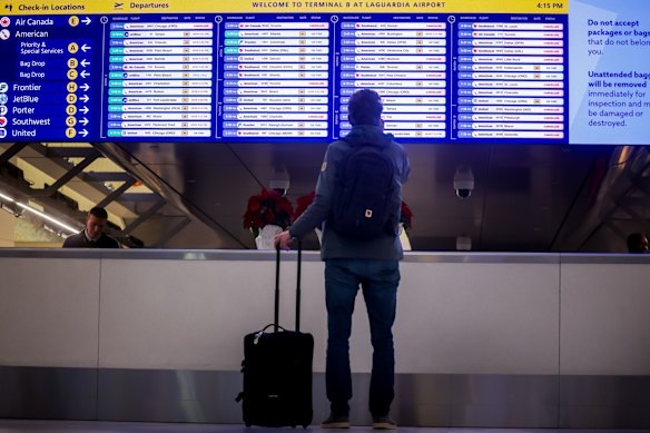 A traveller looks at a departures board at LaGuardia Airport in New York. 