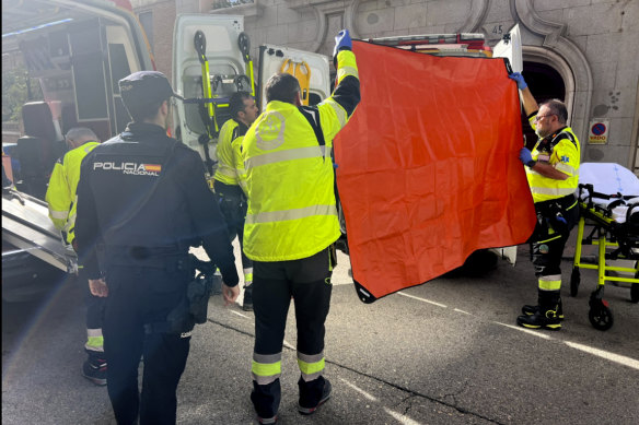 Paramedics cover the view of an ambulance parked on the site of a shooting in Madrid. 