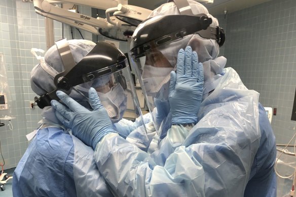 Nurses Mindy Brock and Ben Cayer, wearing protective equipment, look into each other's eyes, in Tampa General Hospital in Florida.