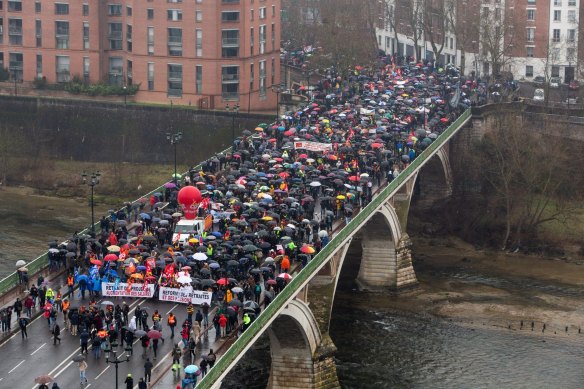 Demonstrators march across the Pont des Catalans bridge on the River Garonne at a protest during a national strike against pension reform in Toulouse, France.