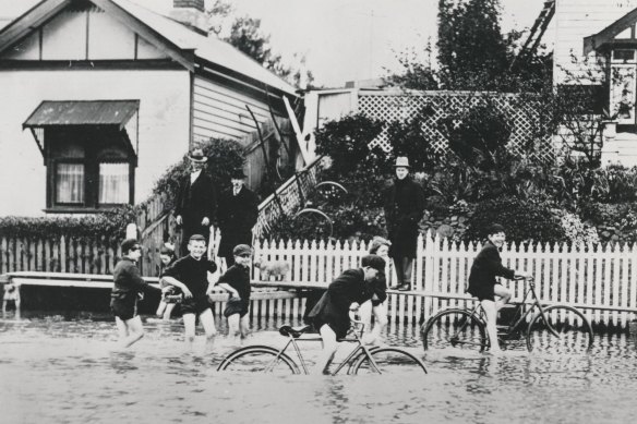 Children ride bicycles in the floodwaters.