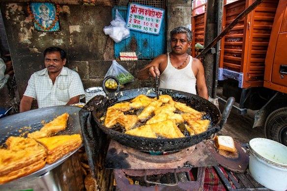 Vendor makanan menjual makanan ringan di pasar di Delhi, India.
