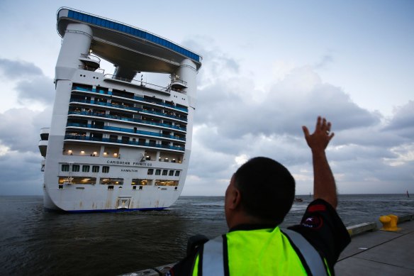 An officer waves off a Caribbean Princess cruise ship in Pasadena, Texas. Princess Cruise Lines' owner, Carnival, will pay a $28 million penalty for pollution breaches. 