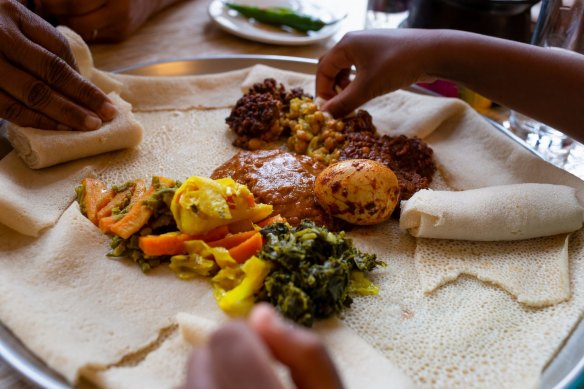 A classic Ethiopian meal will usually consist of at least three or four different dishes such as shiro wat (centre), all served on top of the injera and eaten family style. 