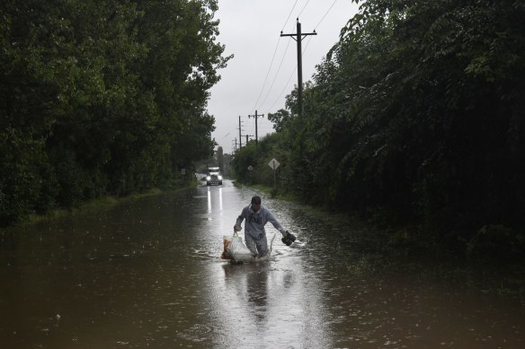 A man wades through floodwater on Old Kurrajong Road after his car became stranded and tow trucks couldn’t retrieve it. 