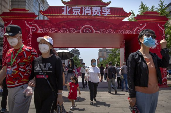 People wearing face masks to protect against the new coronavirus walk at a government event aiming to stimulate consumer demand and consumption in Beijing, Saturday, June 6, 2020. 