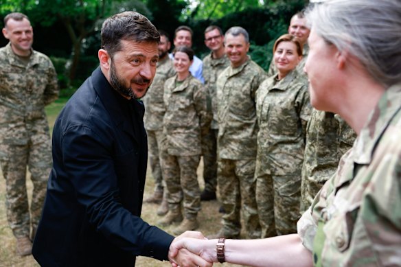 O presidente ucraniano, Volodymyr Zelensky, aperta as mãos com um soldado da Operação Interflex em junho.