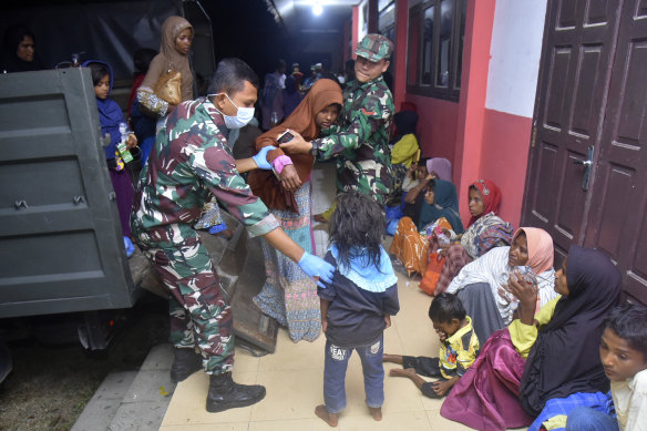 Indonesian soldiers help Rohingya women and children at a temporary shelter after their boat landed in Pidie, Aceh province on Boxing Day.