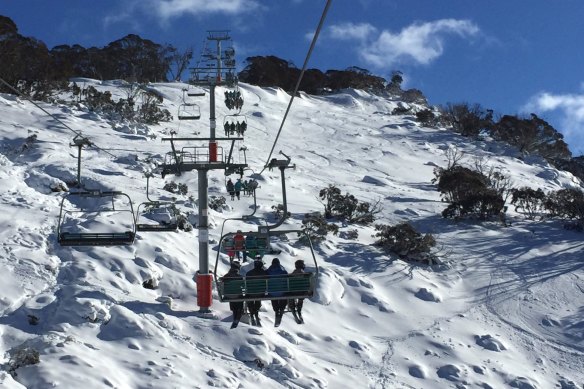 Skiers and snowboarders ride a chairlift at Thredbo in 2017.