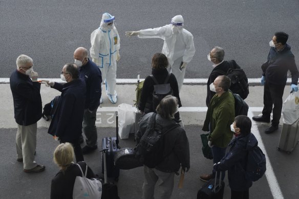 A worker in protective gear directs members of the World Health Organisation (WHO) team in Wuhan, China earlier this year. 