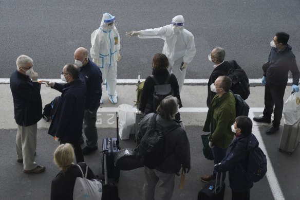 A worker in protective coverings directs members of the World Health Organization (WHO) team on their arrival at the airport in Wuhan in central China’s Hubei province in January. 