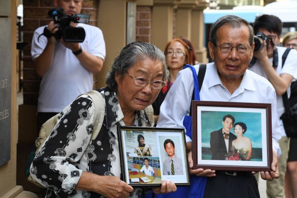 Min Lin's parents hold photos of their murdered relatives outside court in 2017.