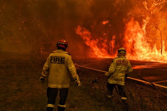 Fire and Rescue attempt to hold the Gospers Mountain fire from crossing the Bells Line of Road in December 2019. 