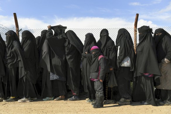 Foreign ISIS wives and children line up near the foreign section of Al-Hawl camp to be taken to the shops in the camp, 2019. 