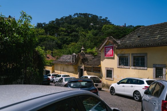 Drivers get stuck on a small Sintra street beneath a banner reading “Chaotic traffic affects everyone: residents and tourists”.