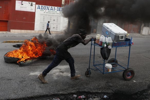 In Haiti, a snow cone vendor pushes his cart past a burning barricade on October 15.