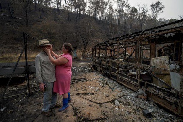 Mark Brooks is comforted by his daughter Kylee on January 9, after returning to the remains of his home near Corryong.