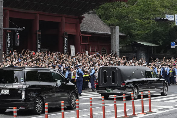 The vehicle, right, carrying the body of former Japanese Prime Minister Shinzo Abe leaves Zojoji temple after his funeral in Tokyo on Tuesday.