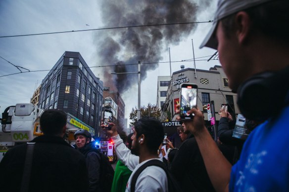 Spectators take images on their phones of firefighters, police and emergency services personnel responding to a large building fire at Surry Hills on May 25, 2023.