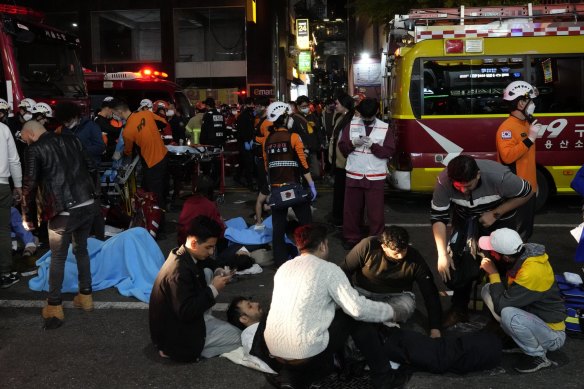 Rescue workers and firefighters try to help injured people near the scene of a crowd surge in Seoul, South Korea.