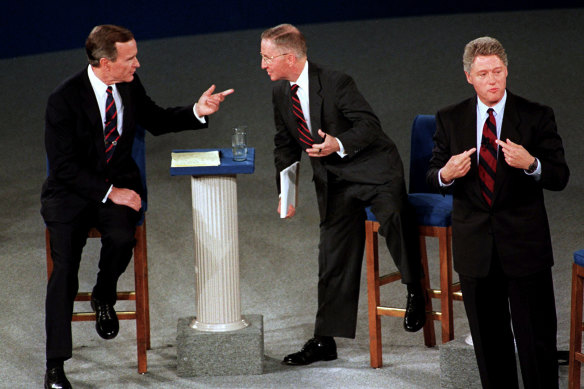 President George H.W. Bush, left, talks with independent candidate Ross Perot as Democratic candidate Bill Clinton stands aside at the end of their second presidential debate in 1992.  