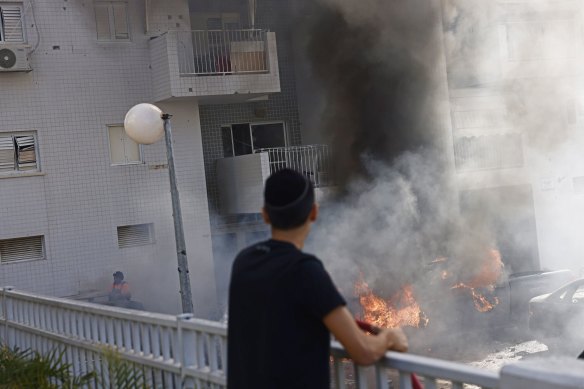 A resident looks at cars on burning after a during a rocket attack in Ashqelon, Israel.