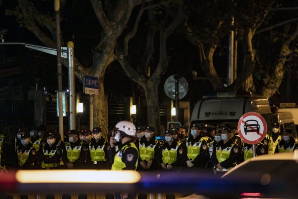 Police officers stand guard during a protest in Shanghai on Sunday night.