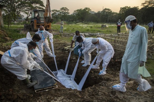 Relatives and municipal workers in protective suits bury the body of a COVID-19 victim in Gauhati, India.