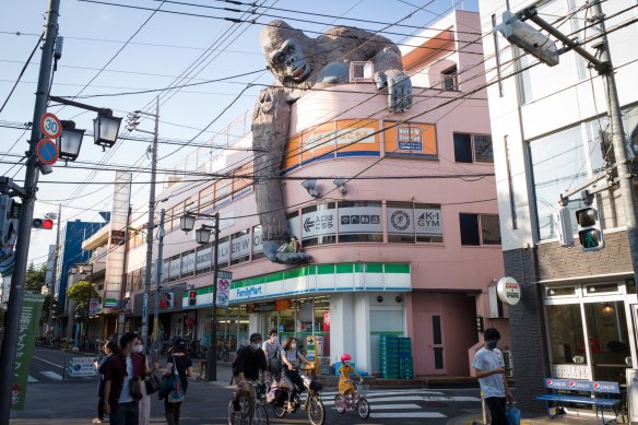 Pedestrians wearing protective face masks walk past a convenience store in the Setagaya district of Tokyo, Japa.