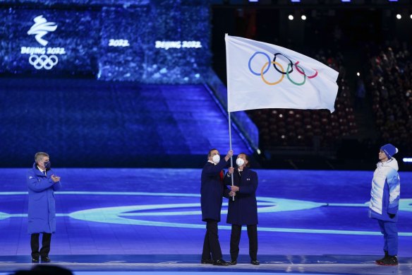 International Olympic Committee President Thomas Bach, left, watches as Giuseppe Sala, mayor of Milan, and Gianpietro Ghedina, mayor of Cortina, take charge of the Olympic flag for 2026.