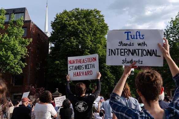 Demonstrators hold signs during a protest in support of international students at Harvard University.