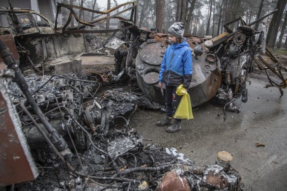 A boy looks at a destroyed Russian tank after recent battles in Bucha, close to Kyiv.