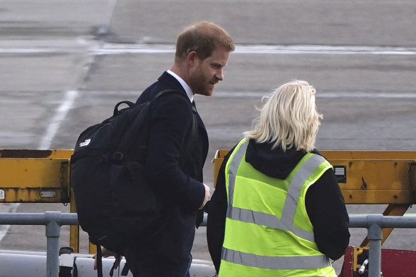 Prince Harry walks towards a plane at Aberdeen airport to travel back to London.