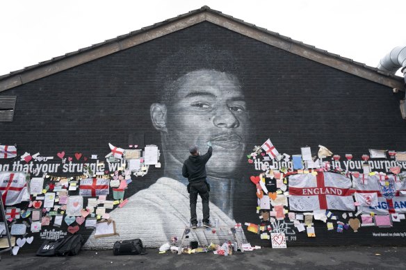 Street artist Akse P19 repairs the defaced mural of Manchester United striker and England player Marcus Rashford.